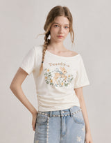 ダイアサマーヴィンテージグラフィックシャーリングワンショルダーTシャツ アイボリー